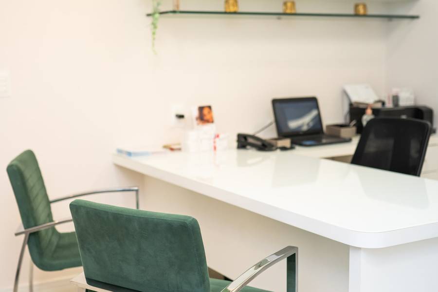 Consultório com mesa, monitores e cadeiras