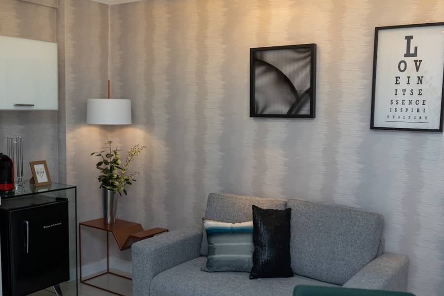 Espaço de descanso com sofá, luminária e quadros